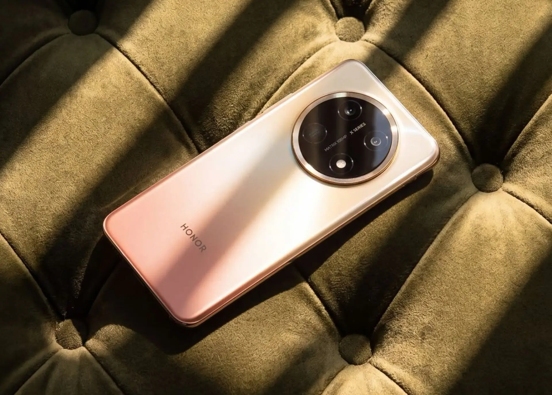 آنر گوشی میانرده با باتری ۱۱ هزار میلیآمپرساعتی میسازد گوشی هوشمند آنر (Honor) X9e Pro با بدنه طلایی روی مبلی سبز